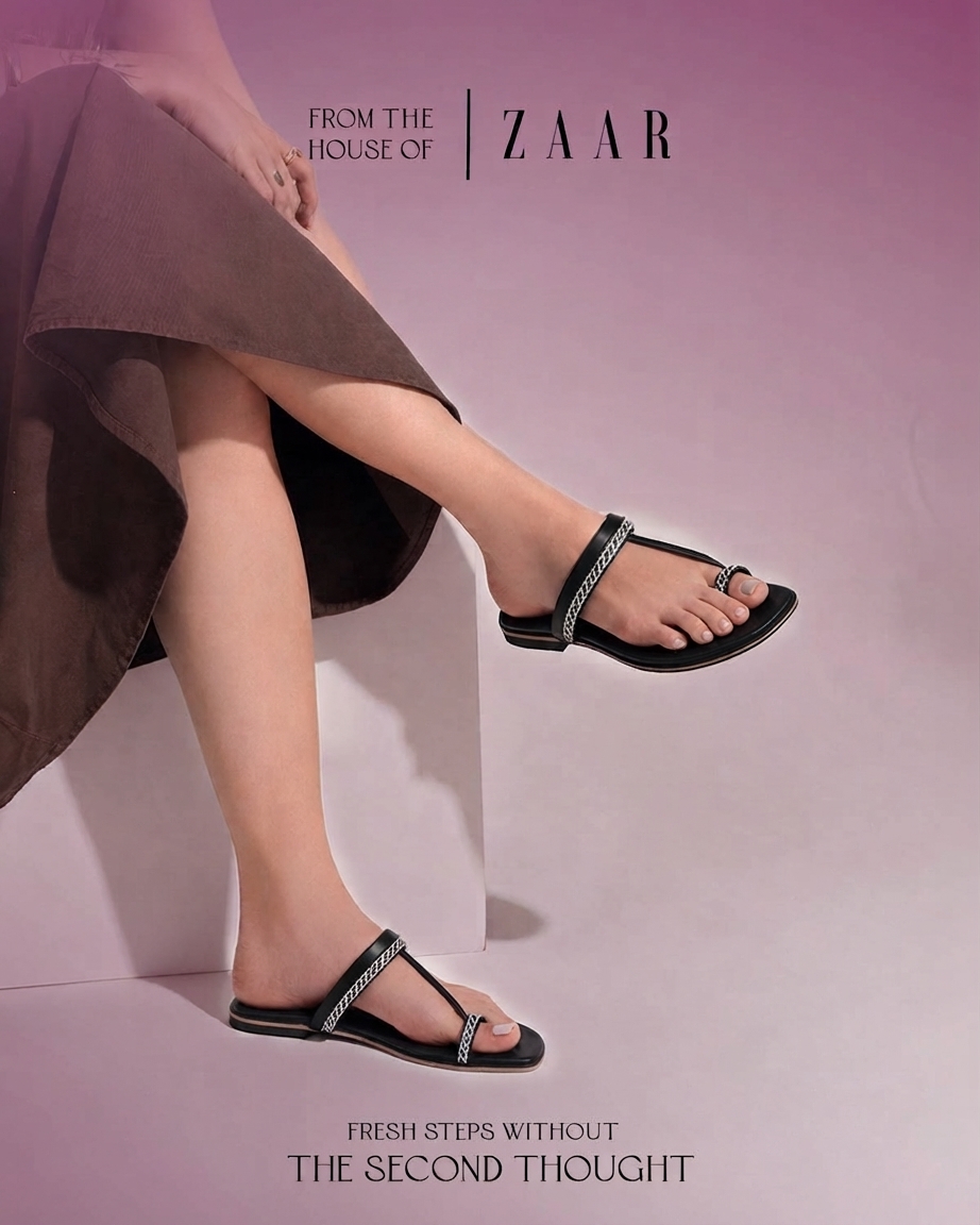 Sira black chain-strap flat sandals against a plum backdrop.